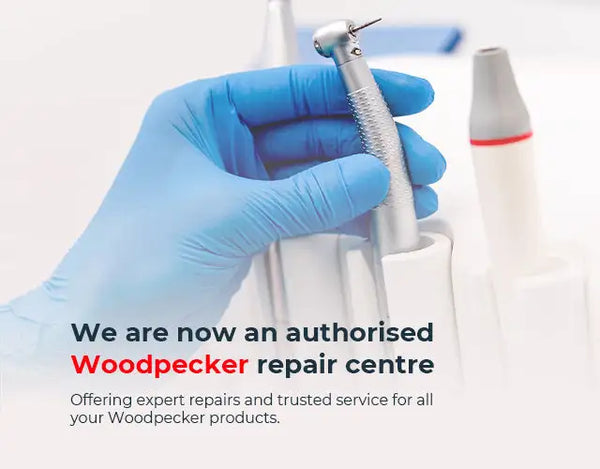 Hand wearing a blue glove holding dental equipment with Woodpecker branding text.